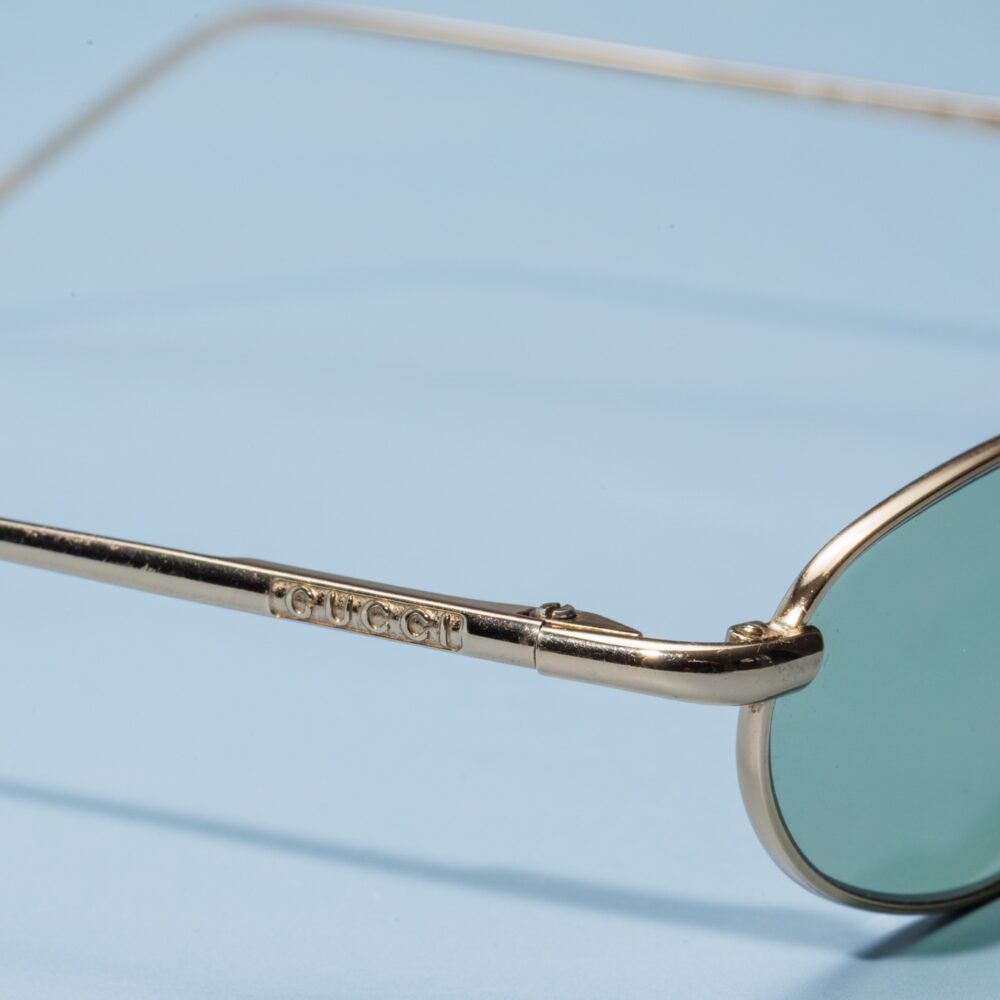 Lunettes de soleil vintage des années 90 de la prestigieuse maison de luxe Gucci. Monture en acier doré fabriquée main en Italie d'un savoir-faire lunetier authentique, avec des verres verts fantastiques. Les lunettes Gucci sont toutes fabriqués à la main, avec des matériaux soigneusement choisis.